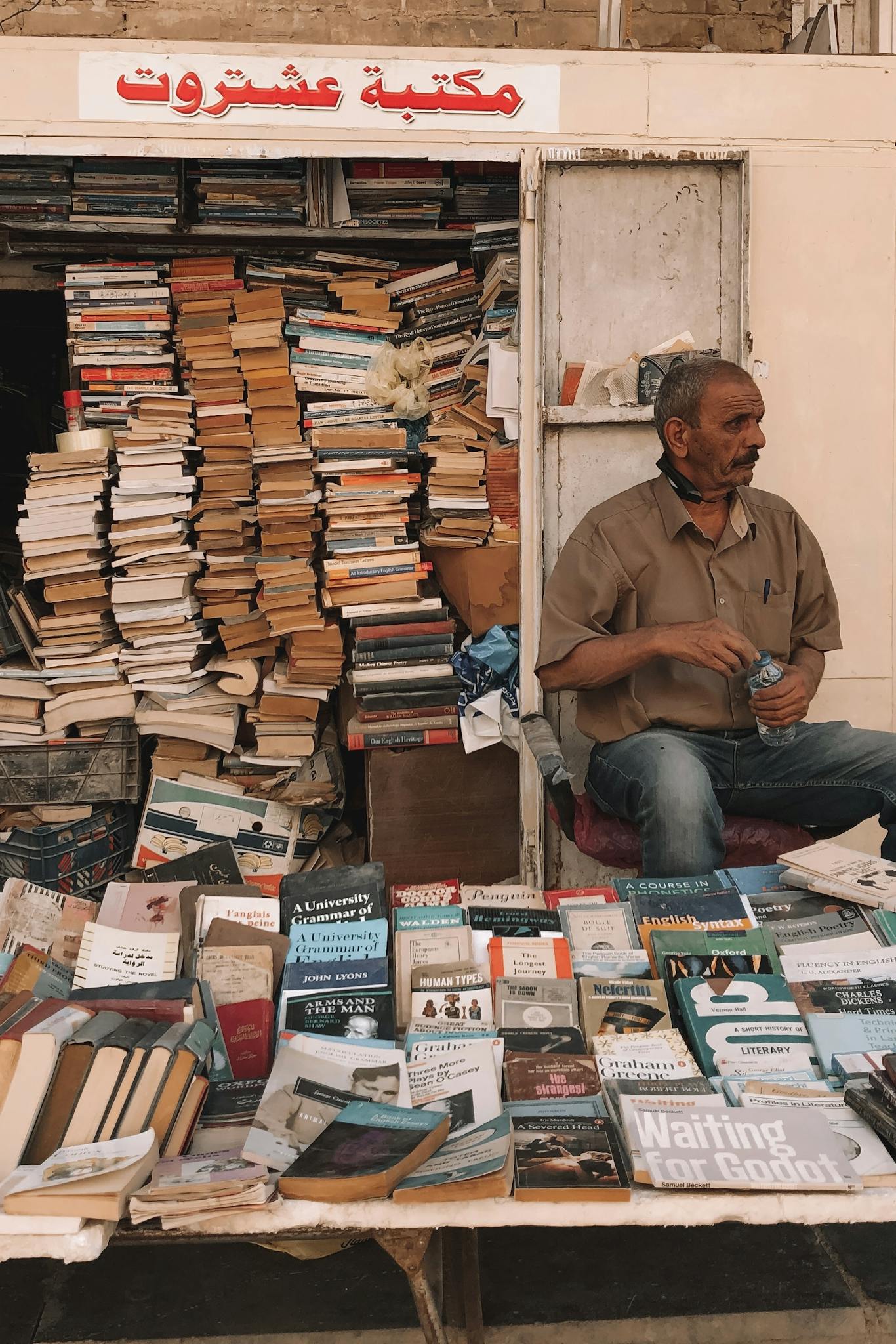 Street vendor selling books at a rustic outdoor stall.