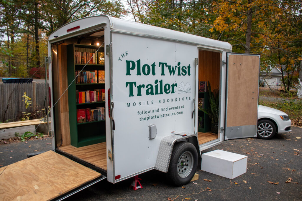 A white enclosed trailer with lettering 'The Plot Twist Trailer'.